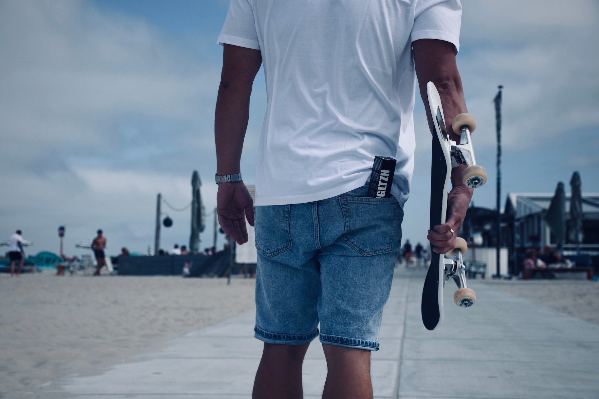 Skater mit Skateboard in der Hand. In der rechten Hosentasche die GLTZN Sonnencreme.