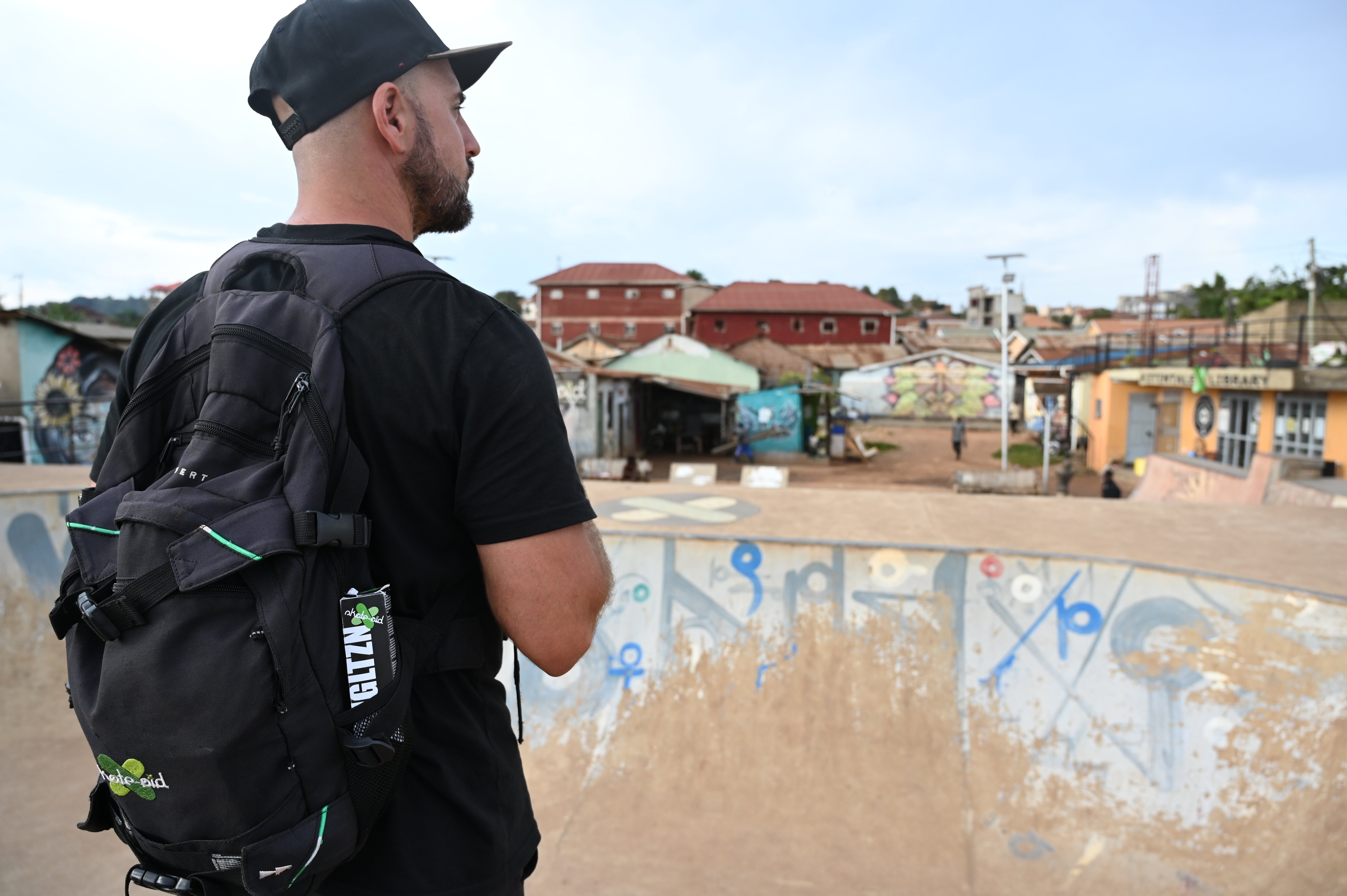 Mann mit Rucksack steht auf einem abgelegenem Skatepark.