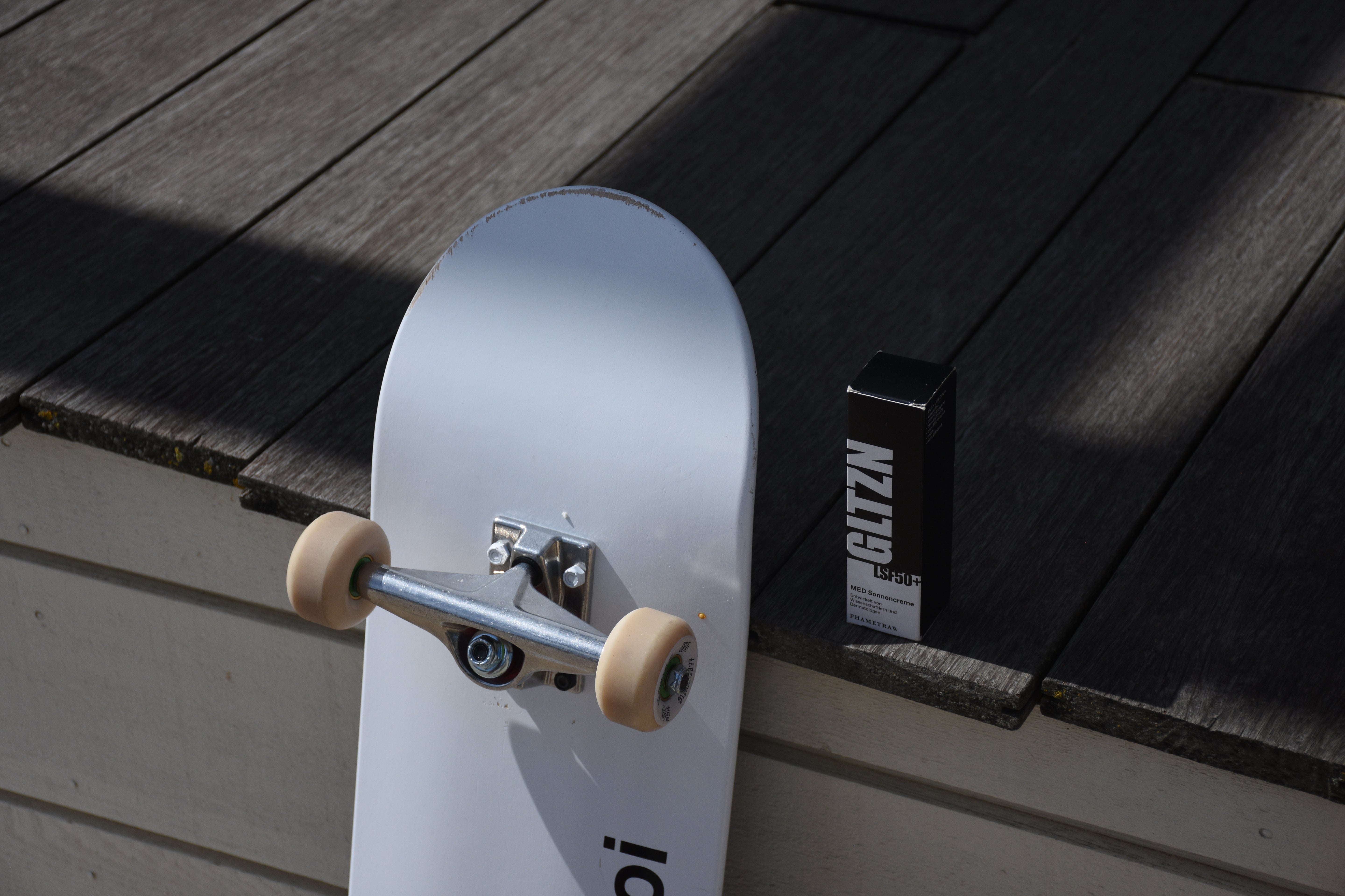 Skateboard angelehnt an Plattform mit GLTZN Sonnencreme neben dran.