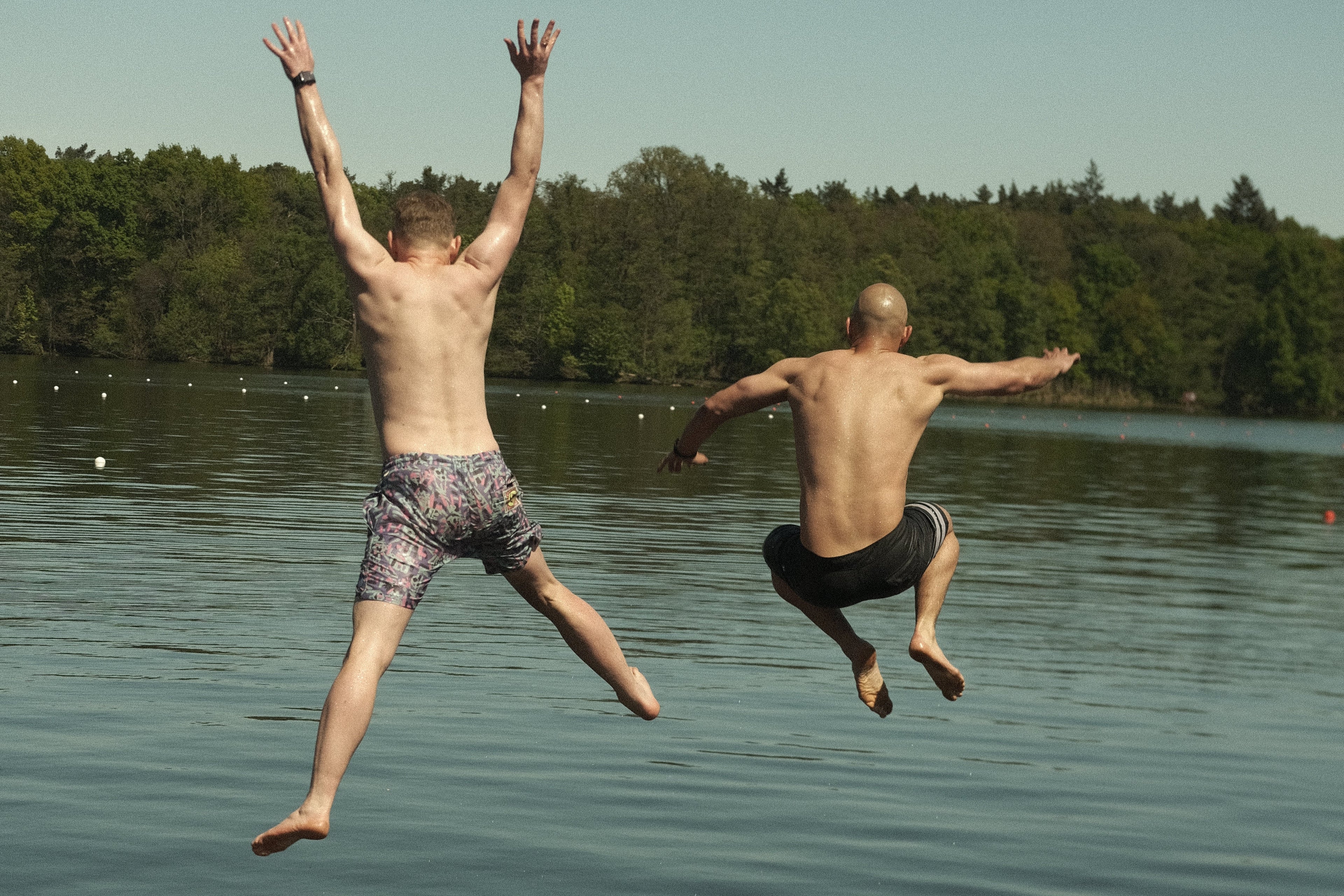 Zwei Männer springen in Wasser.
