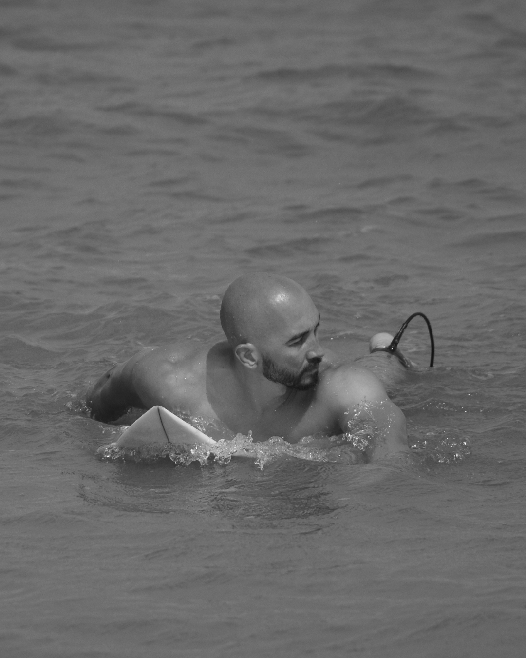 Mann mit Glatze am Surfen im Meer