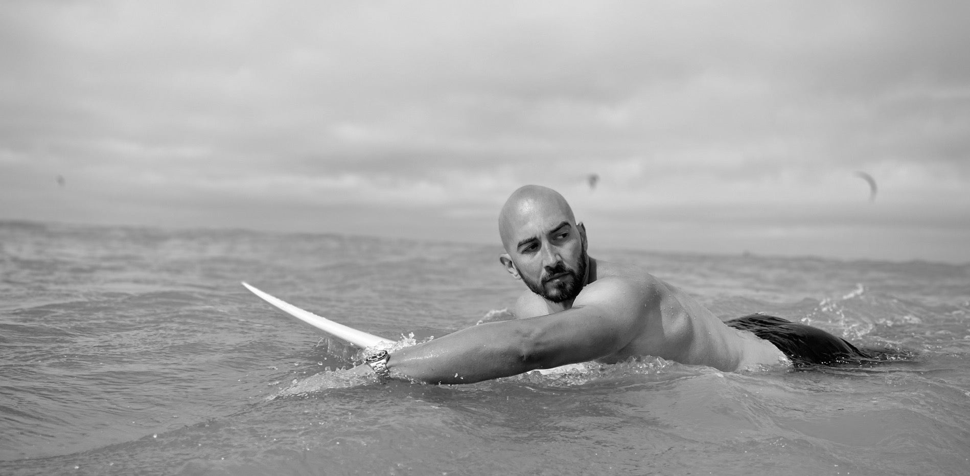 Surfer mit Glatze paddelt im Wasser