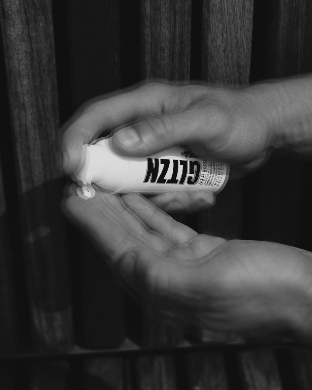 Unscharfe Nahaufnahme von zwei Händen beim Auftragen von Sonnencreme.